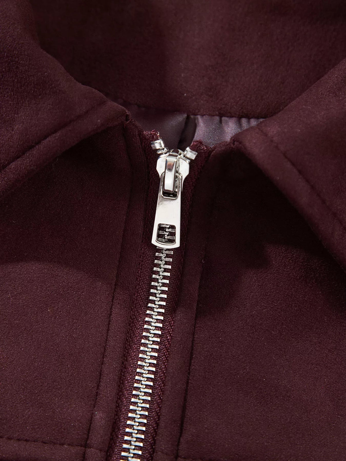Close-up of a burgundy zip-up long-sleeve jacket showing its raised collar, smooth construction, and prominent silver metal front zipper.